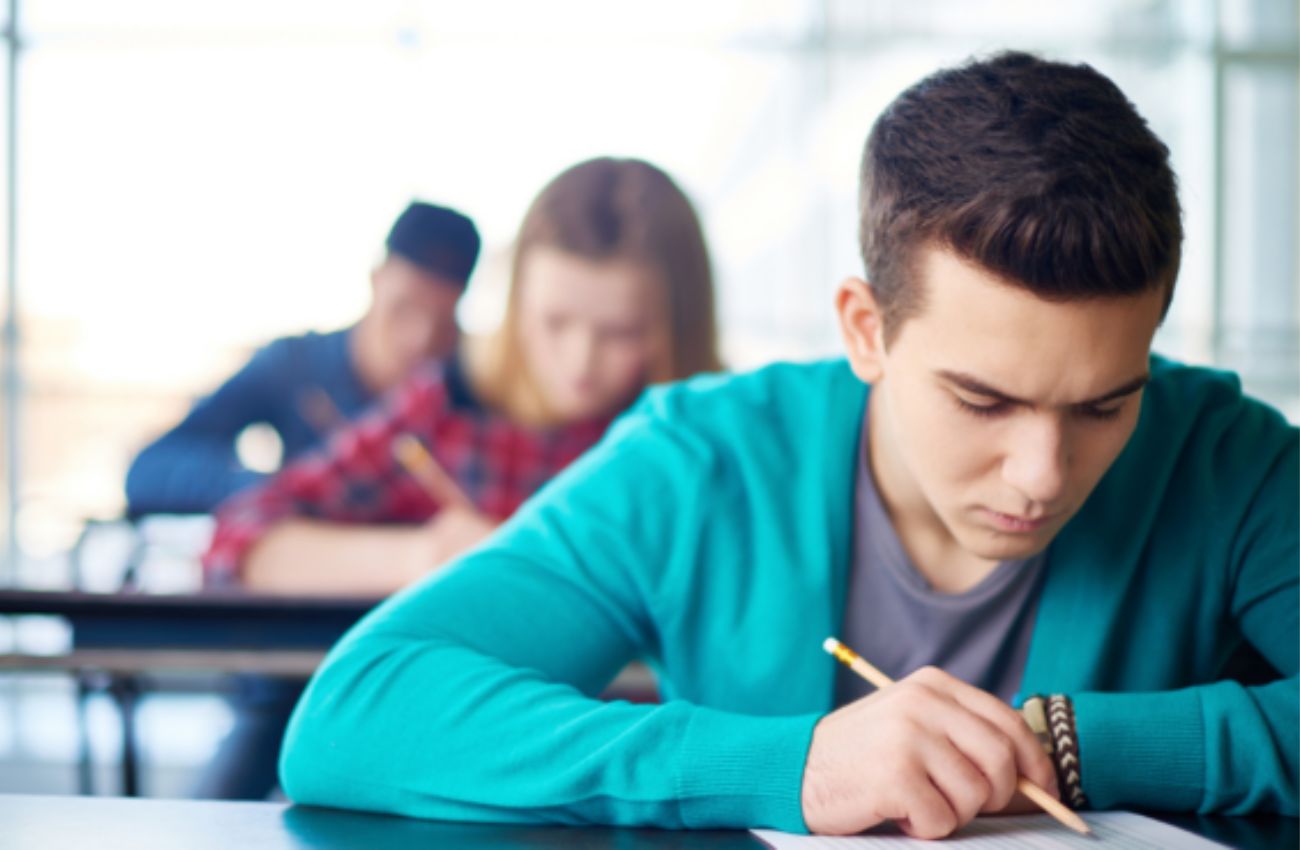 High school students sit at tables taking a test.