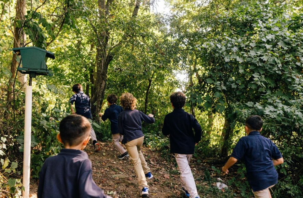 A group of elementary school boys run on a wooded path during their school day at Main Line Classical Academy. 