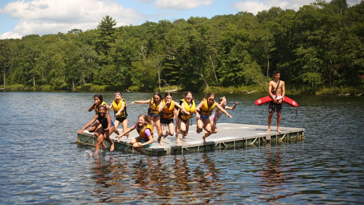 Campers jump off a float in the lake at Camp Speers YMCA.