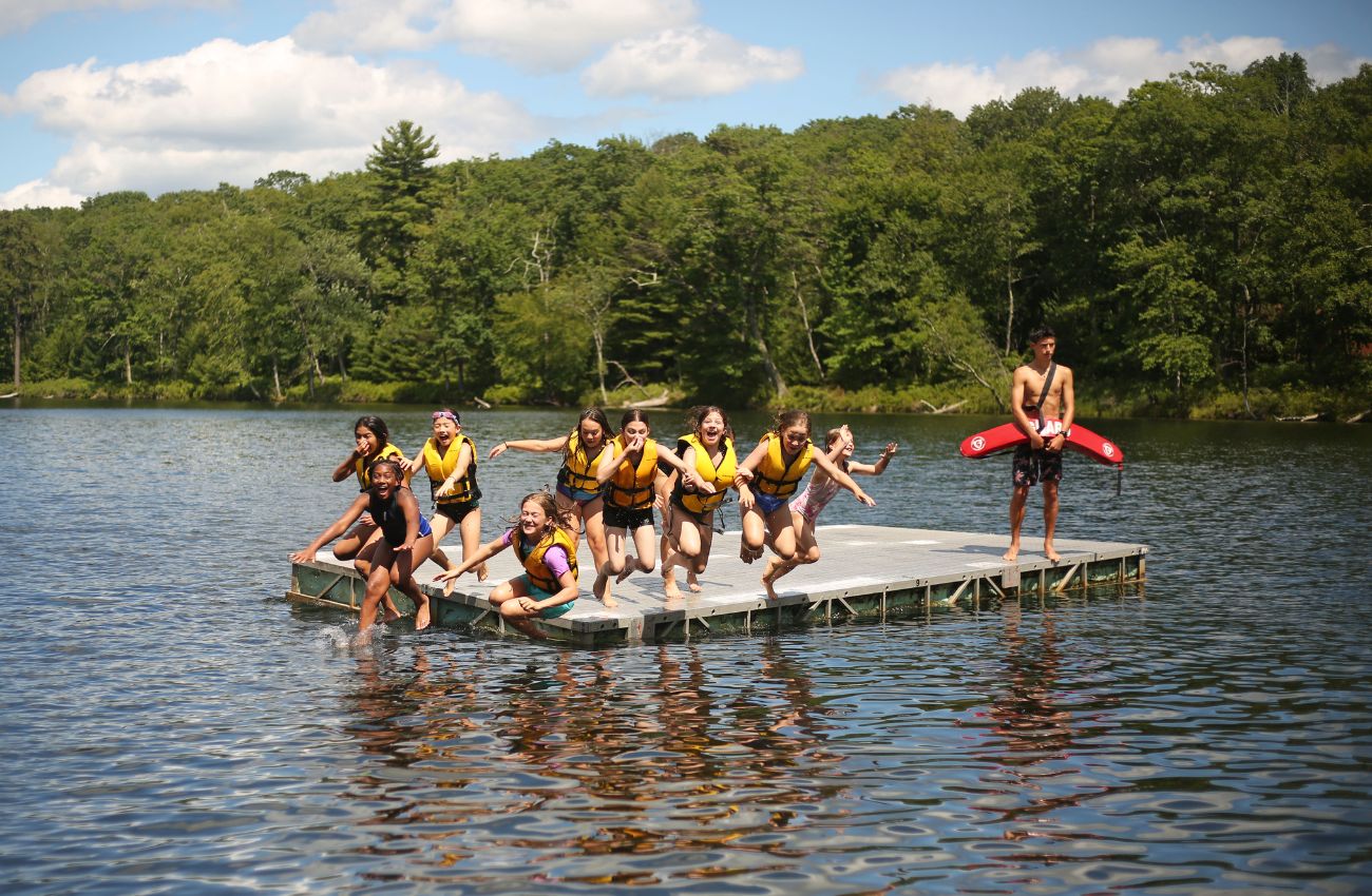 Campers jump off a float in the lake at Camp Speers YMCA.