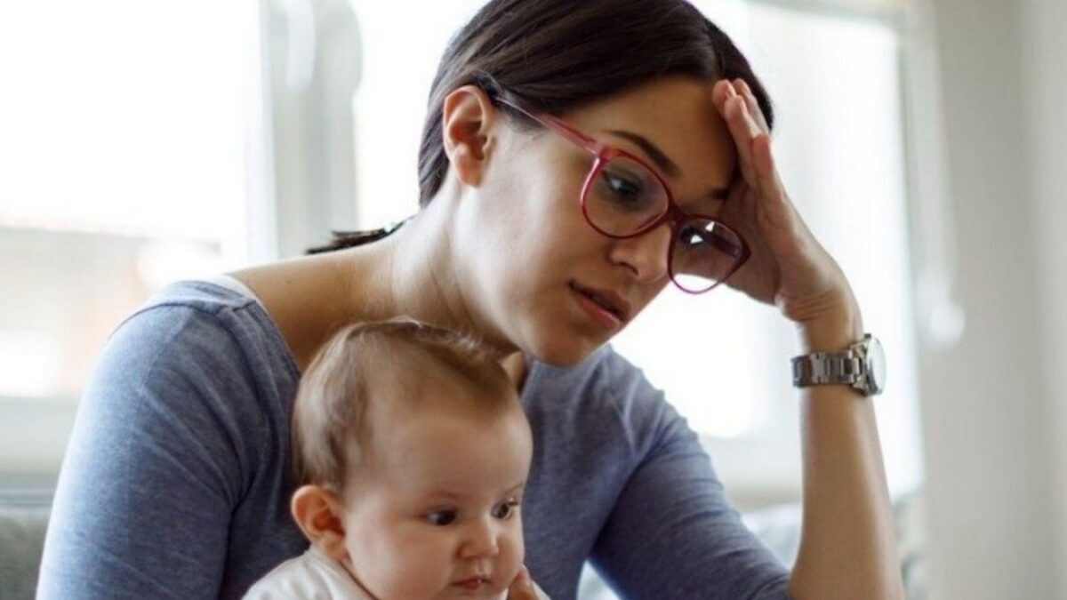 A mom holds her baby, while grappling with the mental load of motherhood.