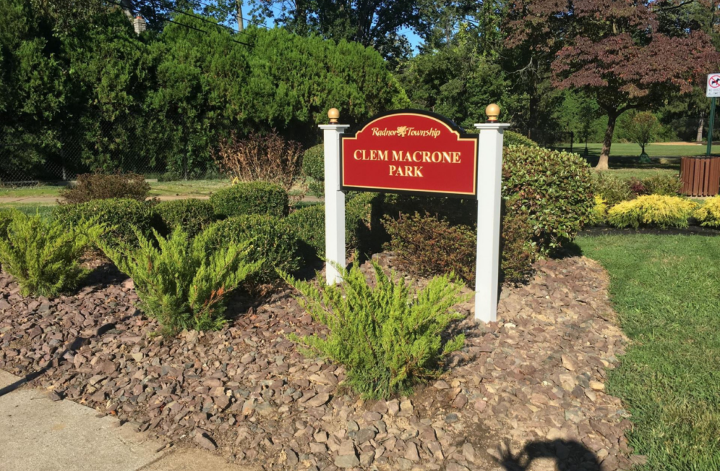 A red sign sits at the entrance to Clem Macrone Park in Bryn Mawr, PA. 