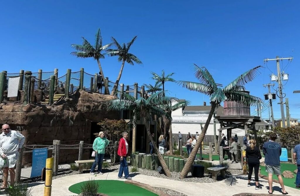 A mini golf course with palm trees and other jungle theme elements. 