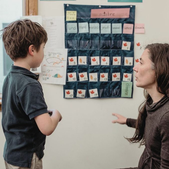 Teacher working with a student on a calendar activity.